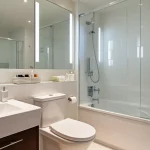 A spotless, modern bathroom with clean tiles, mirrors, and a sparkling sink, showcasing a clean bathroom checklist result.